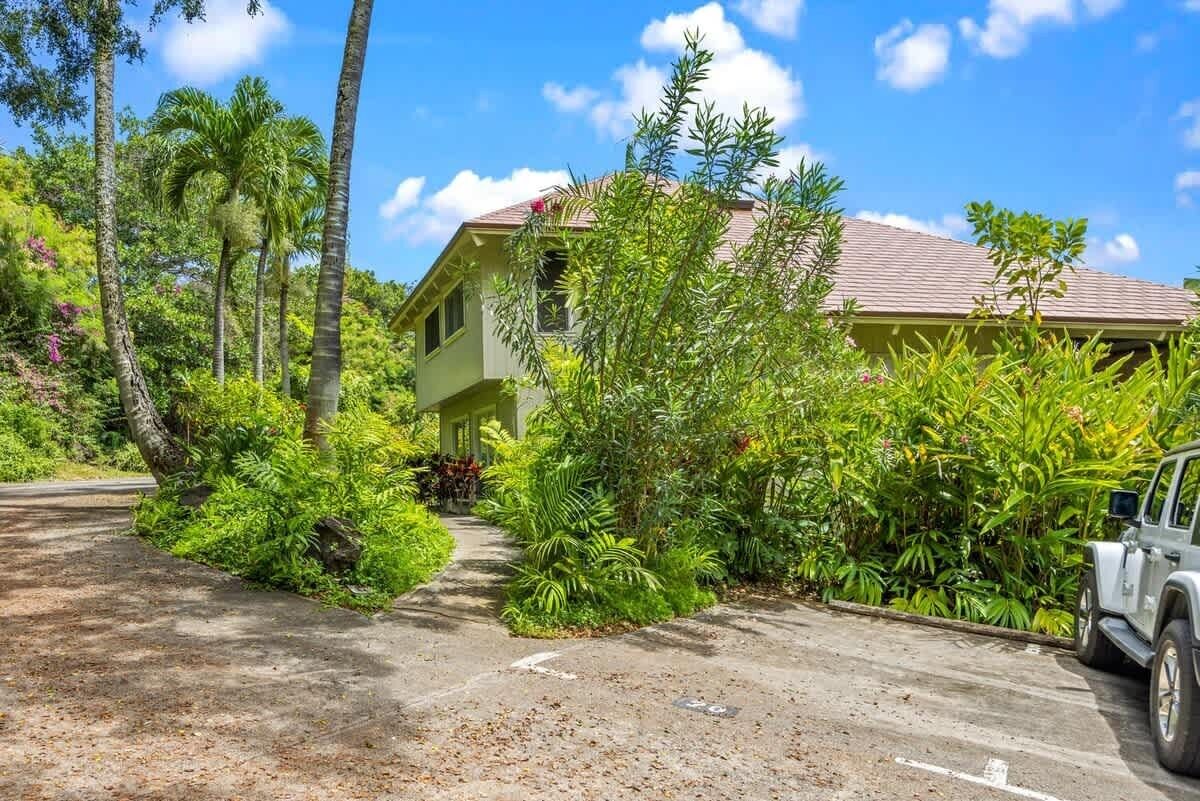 Un bâtiment à deux étages doté d’une façade verdoyante, entouré d’une végétation tropicale luxuriante.