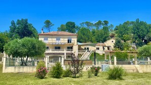 A two-story house with a balcony, surrounded by a fenced yard and trees. - Les terrasses de valerian (Brignoles)