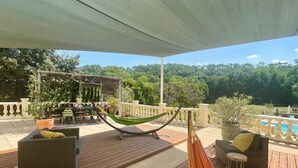 A wooden deck with a hammock, outdoor furniture, and potted plants. - Les terrasses de valerian (Brignoles)
