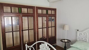 Un dormitorio con cama, mesita de noche, lámpara y armario con varias puertas.