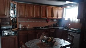 Cocina compacta con armarios de madera, cocina a gas y una mesa de comedor con sillas.