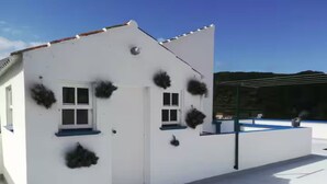 Un edificio blanco con múltiples ventanas y macetas colgantes.