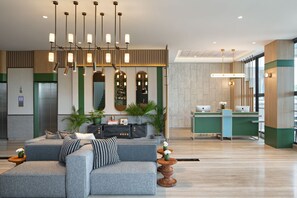 A modern lobby with a seating area, a reception desk, and a large mirror. - MaxOneHotels Kota Harapan Indah Bekasi (Tarumajaya)