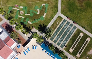 An aerial view of a property with a swimming pool, tennis courts, and a landscaped garden area.