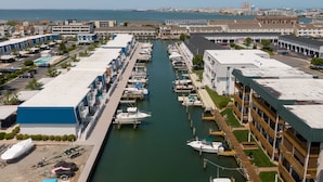 A marina with boats docked, a parking area, and a building with a green roof. - Two Bedroom Townhome On Canal! (Ocean City)