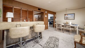A modern kitchen with wooden cabinets, a dining area with a table and chairs, and a bar area with stools. - Two Bedroom Townhome On Canal! (Ocean City)