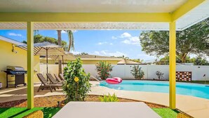 Area piscina con lettini, barbecue e piscina con un cerchio gonfiabile rosso.