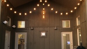 A hot tub under a covered patio with string lights, wooden walls, and a chimney. - Luxury Mountain Retreat Near Midway & Park City – Sleeps 10 (Heber City)