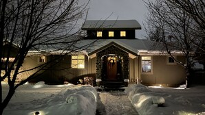 A house with a stone facade, a front porch, and a snow-covered driveway. - Luxury Mountain Retreat Near Midway & Park City – Sleeps 10 (Heber City)
