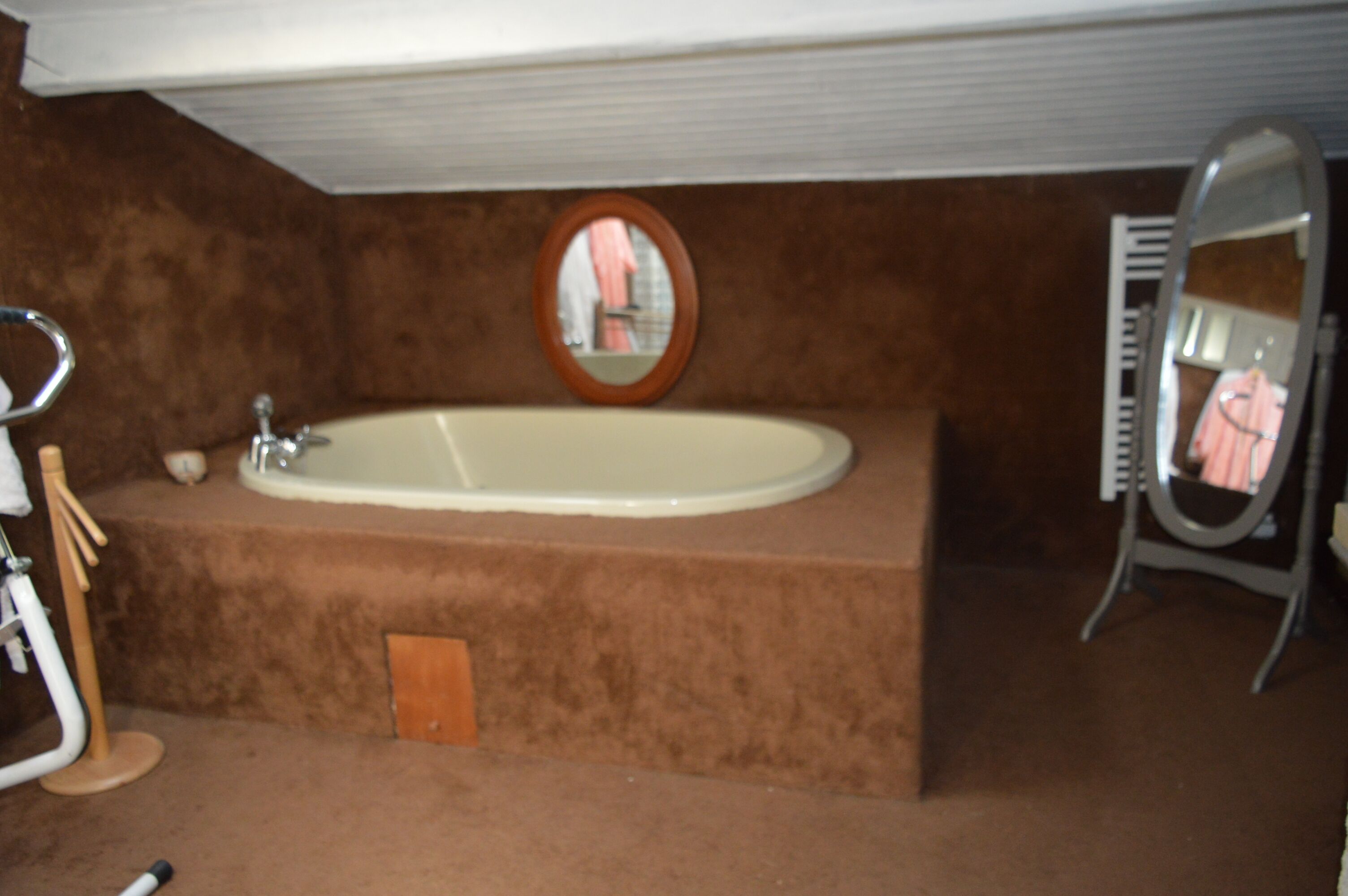 A bathroom with a large bathtub, a mirror, and a towel rack.