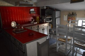A kitchen with a red countertop, white cabinets, and a microwave.