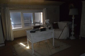 A dimly lit room with a white bed, a bedside table, and a lamp.
