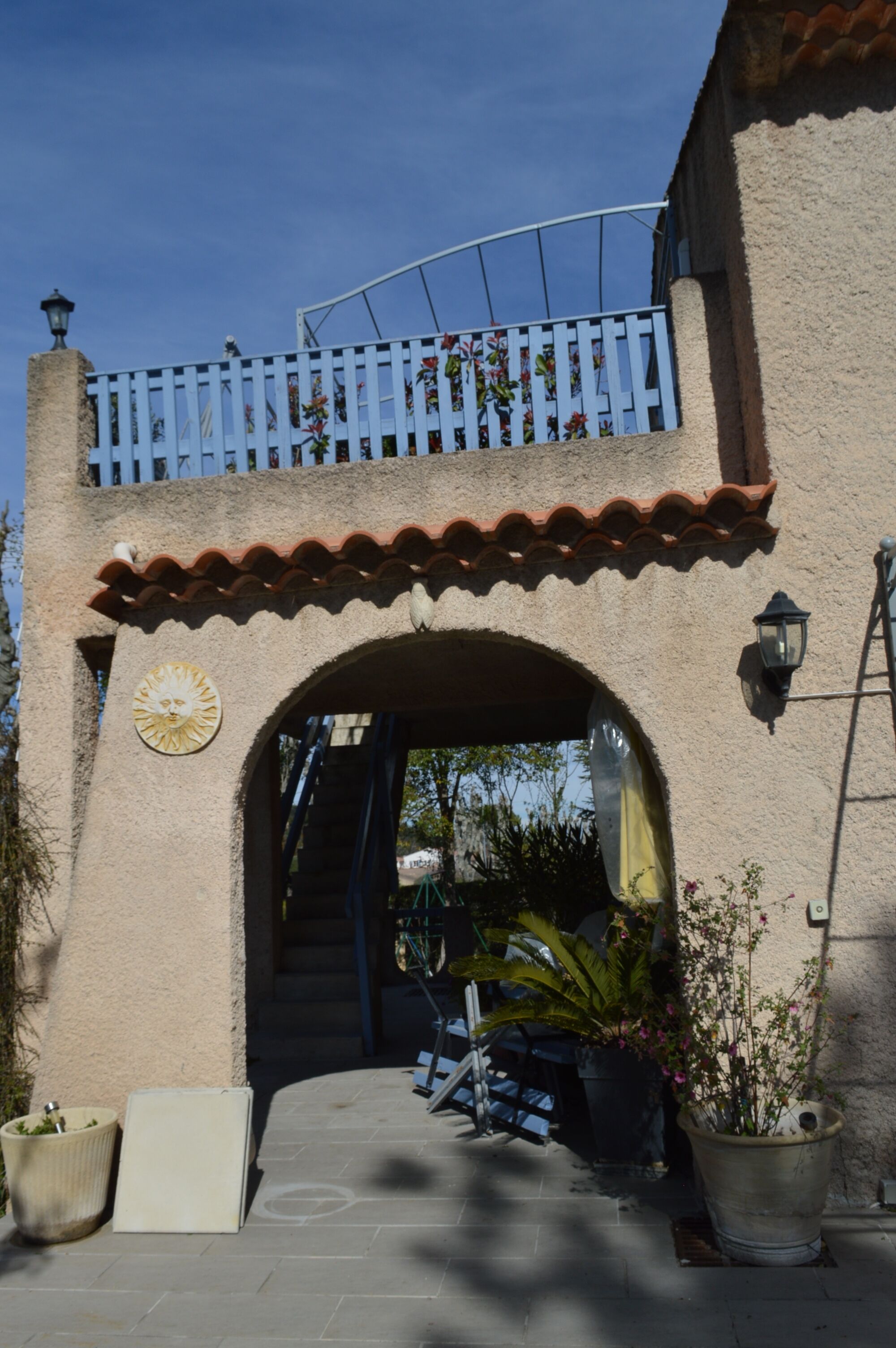 A building entrance with a tiled roof, a balcony with a railing, and a large archway.