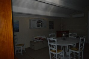 A dining area with a round table, white chairs, and a cabinet.