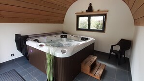 Un jacuzzi en una habitación con paredes de madera, una ventana y una silla.