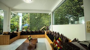 A modern interior with a wooden bench seating area, a wooden table, and a large window offering a view of greenery outside.