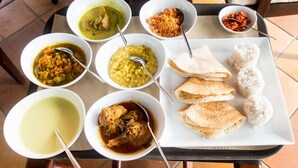 A table with various dishes including curries, rice balls, and flatbreads, suggesting a meal setup.