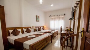 A hotel room with two wooden beds, a small table, a chair, and a mirror.