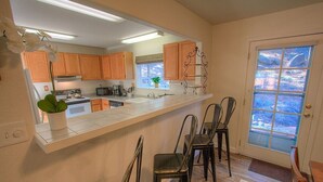 Une cuisine avec des meubles en bois, un plan de travail blanc et une fenêtre donnant sur un beau paysage.