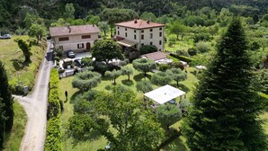 Eine großzügige Villa mit mehreren Gebäuden, umgeben von üppiger Vegetation und einer hügeligen Landschaft.