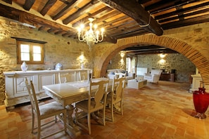 Un interior rústico de piedra con comedor, chimenea y una zona de estar acogedora.