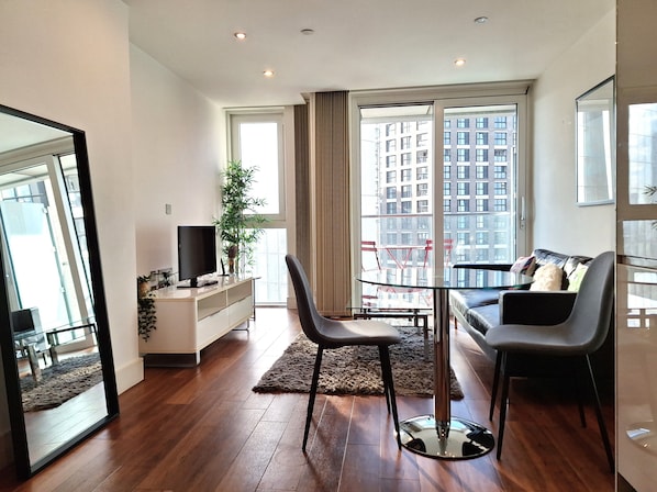 Relax in this stylish living space with a glass dining table, comfortable sofa, and flat-screen TV.