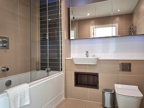 Enjoy a contemporary bathroom with a wall-mounted sink, standalone toilet, and glass-enclosed shower.