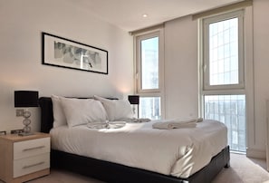 Relax in a serene bedroom with a neatly made bed, black headboard, and bedside table with a lamp.