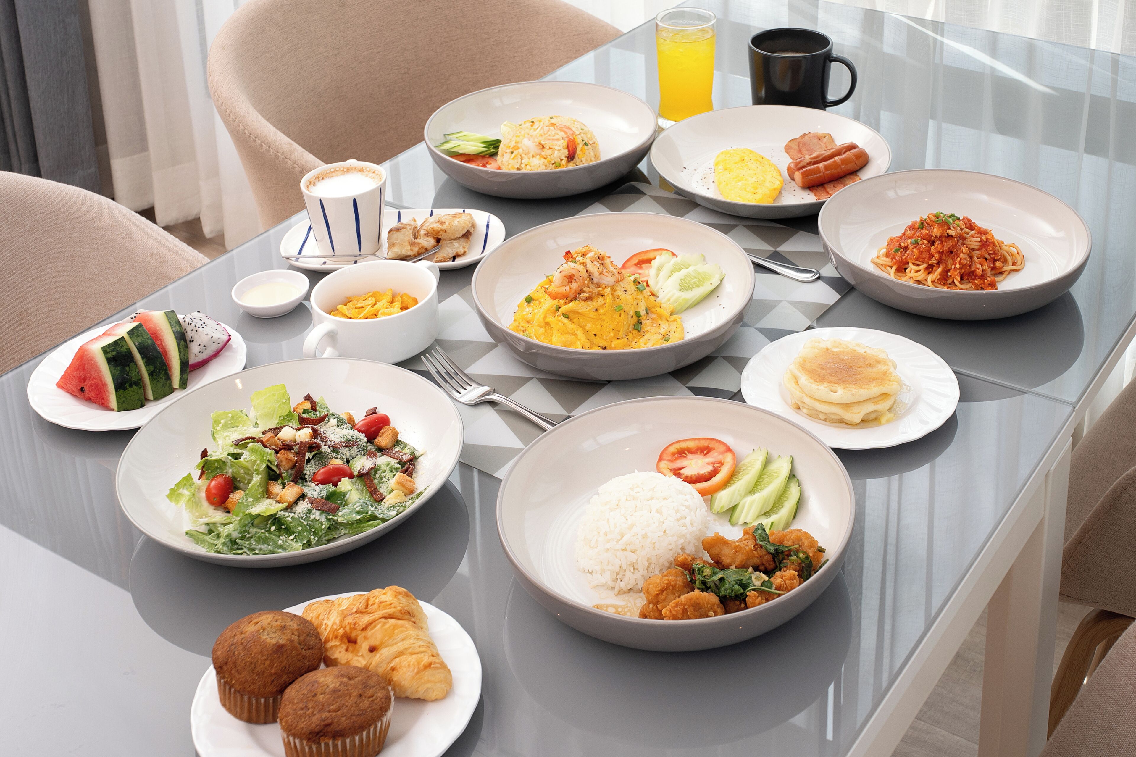 Un bufé de desayuno con diversos platos, entre ellos huevos, panqueques y fruta.