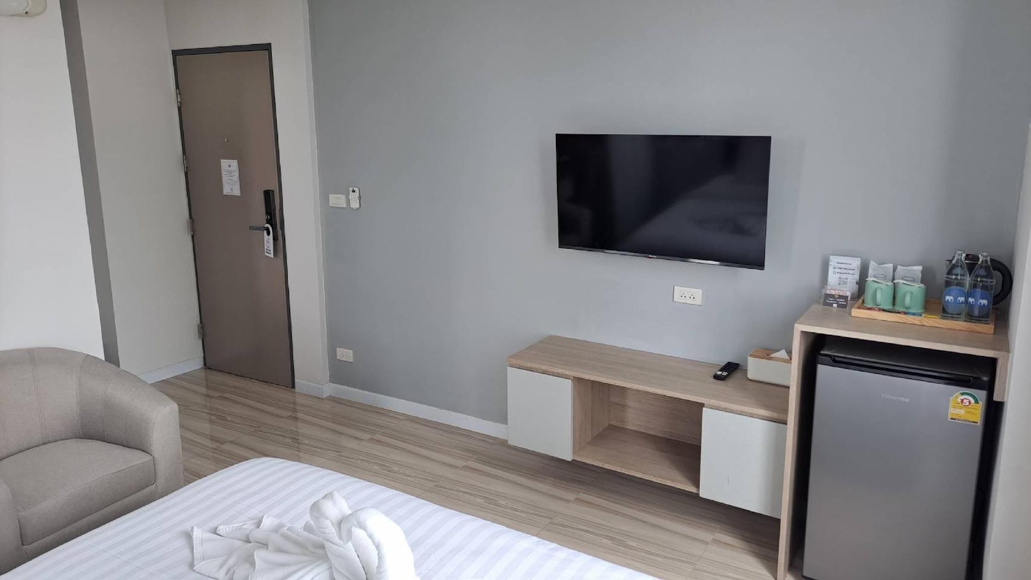 Una habitación de hotel con cama, escritorio, televisor, refrigerador y una silla.