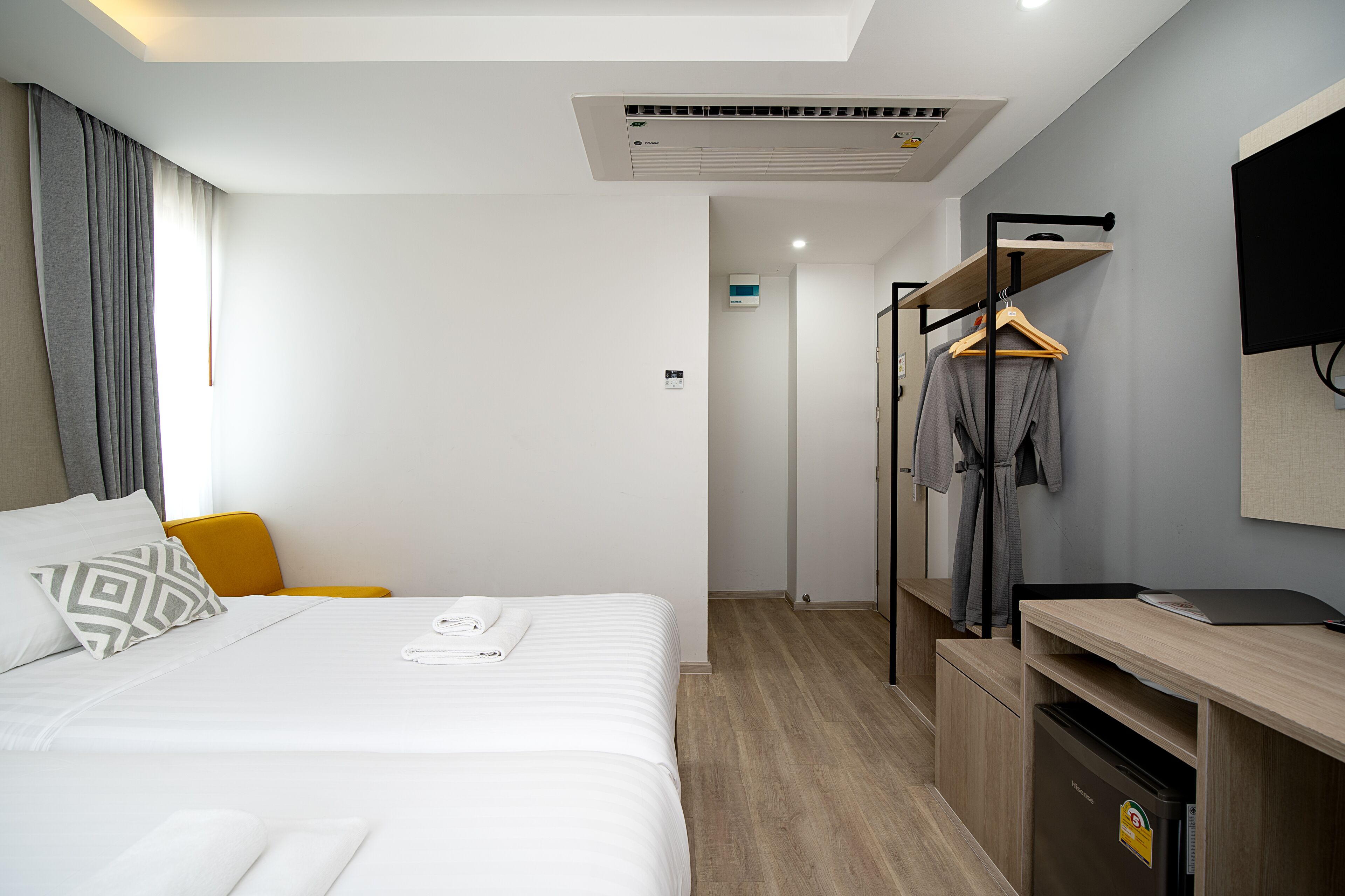 A hotel room with a bed, a desk, a wardrobe, and a television.