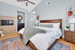 A bedroom with a bed, bedside tables, a ceiling fan, a fireplace, and a rug. - Near Oceanside Pier! Pirate's Treasure (Oceanside)