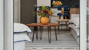 A modern hotel room with a large window, a dining area with a table and chairs, a wicker hanging light fixture, and a small kitchen area. - Naxos Blue Dream Villa With Pool (Naxos)