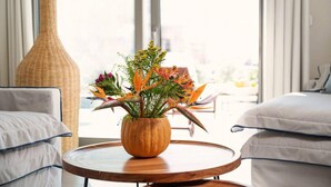A room with a round wooden table, a large vase with flowers, and a view through large windows. - Naxos Blue Dream Villa With Pool (Naxos)