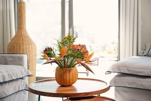 Relax in a stylish room with a round table, floral arrangement, and comfortable sofa.