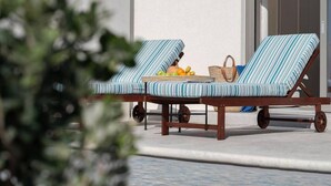 Two lounge chairs with striped cushions, a wicker basket, and a bottle of water on a tiled floor. - Naxos Blue Dream Villa With Pool (Naxos)