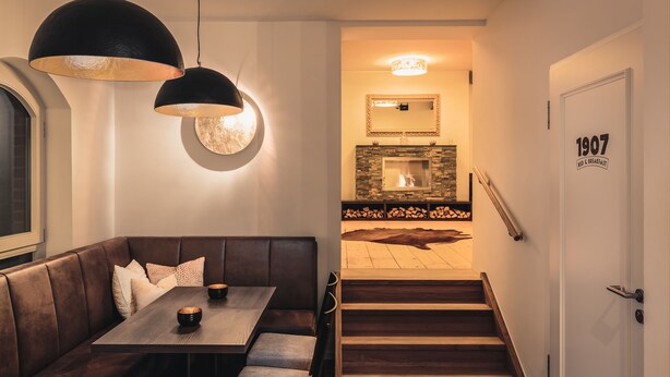 Un intérieur moderne avec un escalier en bois, un coin repas avec un banc et une cheminée.