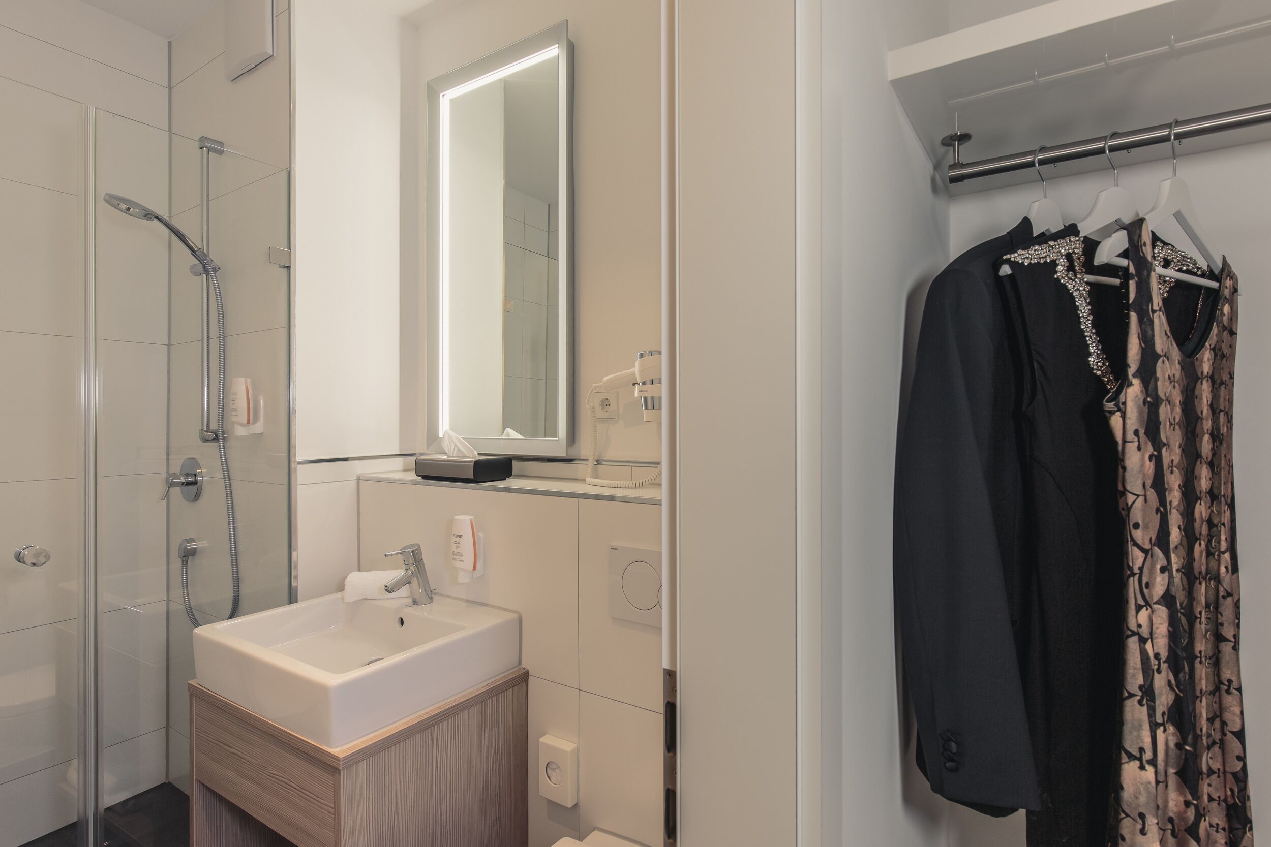 A modern bathroom with a glass shower enclosure, a white sink, and a mirror above it.
