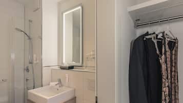 A modern bathroom with a glass shower enclosure, a white sink, and a mirror above it.
