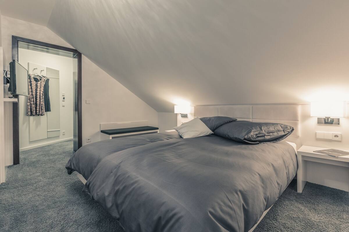 Un dormitorio con una cama grande, una mesita de noche y un espejo.