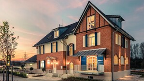 Une maison à deux étages avec une façade en briques, de grandes fenêtres et un porche couvert.