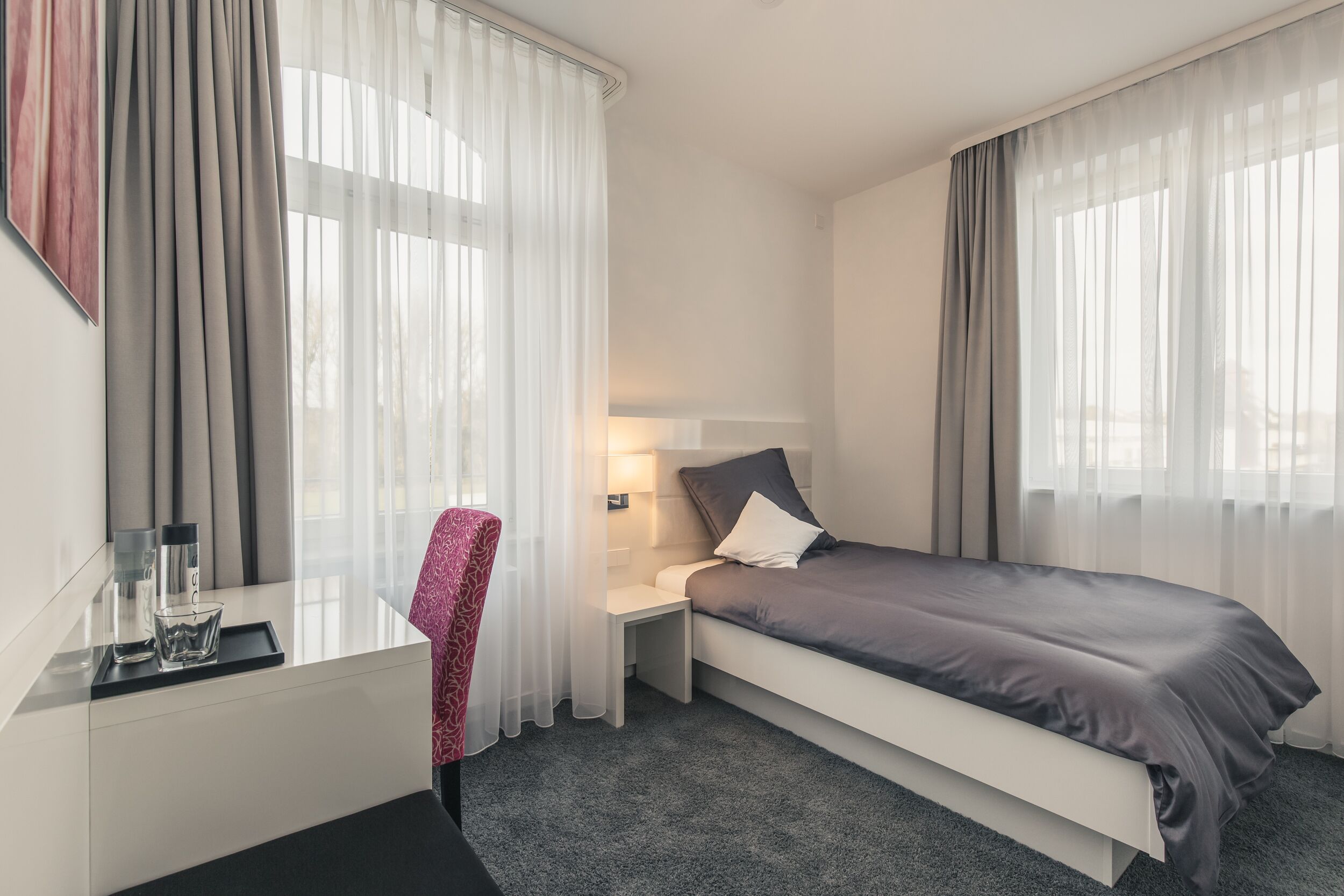 Una habitación de hotel moderna con cama, mesita de noche y una silla.