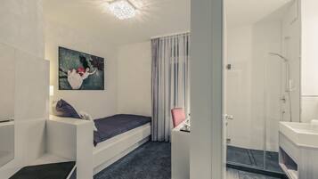 Un dormitorio moderno con cama, escritorio, un cuadro y zona de ducha.