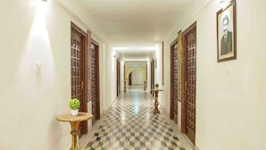 Un pasillo con piso de cuadros, puertas de madera y una pequeña mesa con una planta.