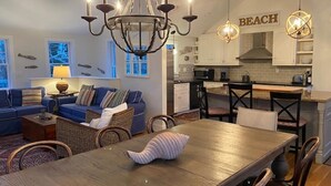 Ein modernes Wohnzimmer mit Essbereich, einer Küche und Blick aufs Meer.