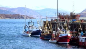 A harbor with several boats docked, a pier with structures, and a mountainous backdrop. - Popular Comfortable Well Equipped Cottage in Peaceful Ullapool Street w Parking (Ullapool)