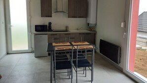 Une cuisine moderne avec un coin repas, un four à micro-ondes, une machine à café et un réfrigérateur.