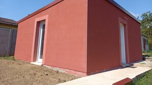 Un petit bâtiment d’un seul étage, à la façade rouge et aux portes blanches.