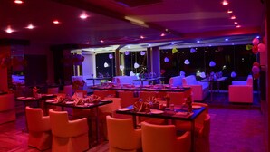 A restaurant with tables and chairs, balloons, and a view through large windows. - JAI MAATA GRANDEUR (Shimoga)