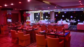 A restaurant with tables set for dining, chairs, and a bar area. - JAI MAATA GRANDEUR (Shimoga)